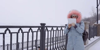一名年轻女子在冬天的户外使用数码平板电脑