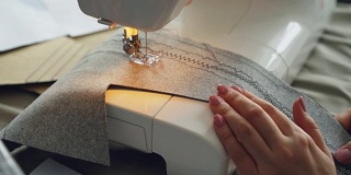 缝纫机，织物和修剪过的女性手的特写镜头。服装制造工艺概念。光线柔和的颜色