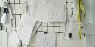 在服装设计工作室墙壁上拍摄的黑白草图、图纸和标注女装尺寸的笔记。创建新的集合概念。