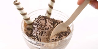 冰淇淋碗里的冰淇淋，上面装饰有威化饼卷。用木勺舀冰淇淋。