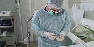 有趣的视频，一名外科医生从消毒设备中拿出医疗器械，并在他的手上扔了一个夹子。穿着专业服装的医生在这家医院工作
