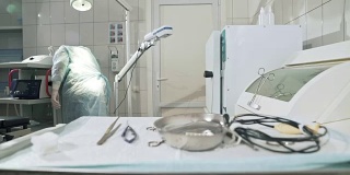 外科医生在医院工作，在手术前准备医疗器械。医生戴眼镜，穿工作服，无菌口罩和晨衣。45、理念健康，工作在诊所。手术工具手术刀，钳，托盘