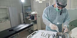 医院的外科医生在手术前给医疗器械消毒。医生戴眼镜，穿工作服，无菌口罩和晨衣。45、理念健康，工作在诊所。手术工具手术刀，钳，托盘