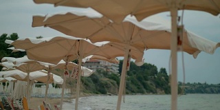 海边有风的天气。空旷的海滩和摇晃的遮阳伞，希腊