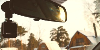 在冬天的乡村慢镜头中驾驶汽车。夕阳在后视镜