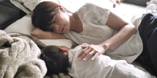 年轻的亚洲母亲爱抚小男孩在床上的早晨