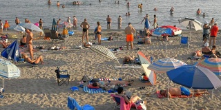 度假者在海滩上放松，在大海中沐浴，希腊