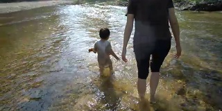 小男孩和妈妈一起在小溪里玩耍。