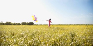 女人拿着彩色气球在草地上奔跑