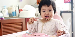 4K:高椅上可爱可爱的女婴。婴儿吃手指食物和玩耍的肖像