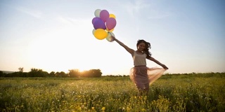 日落时分，一个女人拿着气球在草地上奔跑