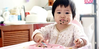 4K:高椅上可爱可爱的女婴。婴儿吃手指食物和玩耍的肖像
