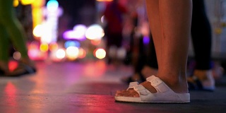 古:晚上，在曼谷唐人街拥挤的街道上，女人脚踩着过马路