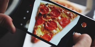一个时髦的男人在餐馆用手机相机拍摄食物
