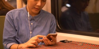 泰国女子晚上在火车上玩智能手机