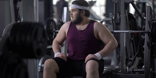 心烦意乱的男人看着自己的胖肚子，渴望减肥，去健身房锻炼，运动