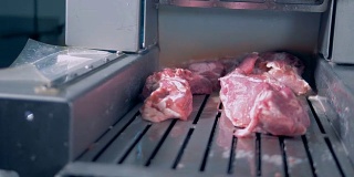 一个工人把肉放到绞肉机上。
