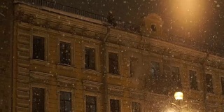 人把雪从屋顶上扔下来。晚上城里下大雪