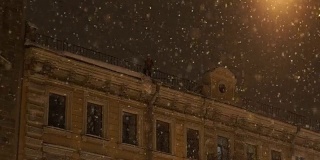 人从屋顶上扔下雪。晚上城里下大雪