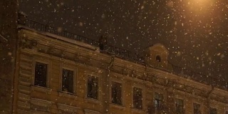 人从屋顶上飘落雪。晚上城里下大雪