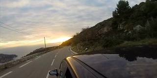 汽车在高速公路上朝着日落，海岸线在山脚下