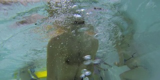 拿着水下相机拍人们在游泳池游泳的视频