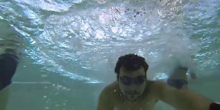 一个拿着相机的人跳进游泳池，玩得很开心