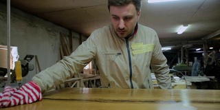 木匠把桌子的木头表面擦亮。