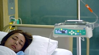 年轻美丽的病人女人睡在医院VIP房间的床上模糊运动输液泵机。视频素材模板下载