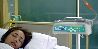 年轻美丽的病人女人睡在医院VIP房间的床上模糊运动输液泵机。