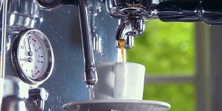 浓缩咖啡从经典的咖啡机倒入小的白色杯子。