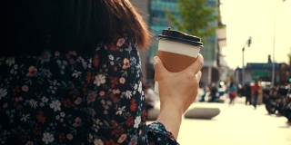 年轻女子拿着咖啡杯走在街上