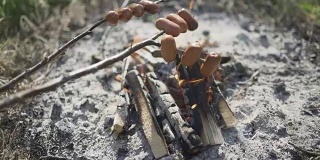 在篝火上烤肥香肠。捷克乡村流行的户外活动。在篝火旁煮香肠。