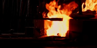 一个铁匠扇火焰的特写镜头，使用工具防止灰烬，火花飞溅到一边的慢动作。铁匠的手的特写