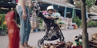 亚洲妇女和男婴在跳蚤市场买装饰品。