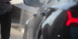 男人用高压水冲洗他的车。户外慢镜头