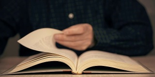 男性在近距离阅读时用手翻动书页。人阅读的书