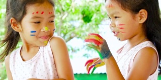 两个亚洲女孩玩着，笑着，玩着她们的绘画手，慢动作拍摄100帧/秒
