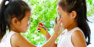 两个亚洲女孩玩着，笑着，玩着她们的绘画手，慢动作拍摄100帧/秒