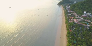 航拍:在海滨度假胜地上空飞行，人们在海滩上散步。