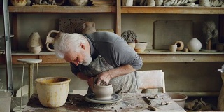 熟练的老陶工在工作场所的转轮上制作陶瓷壶。创作工艺，传统陶艺，趣味爱好理念。