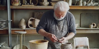 一位经验丰富的手工艺人在舒适的工作环境中制作陶瓷碗，并将其固定在陶器上。陶艺、职业、爱好概念。