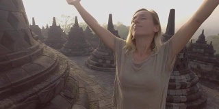 4K分辨率的视频旅行女孩拥抱日出在婆罗浮屠寺，印度尼西亚。People discovery Asia概念