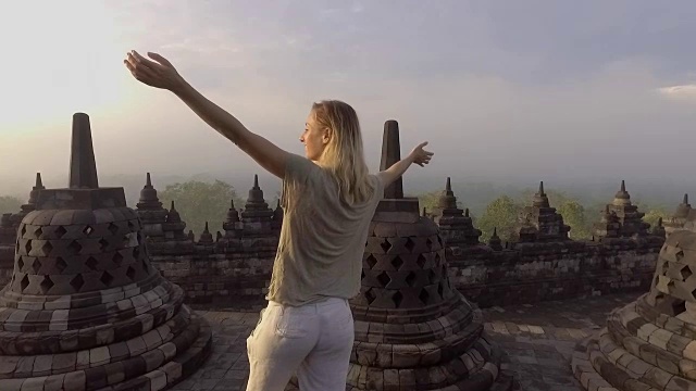 旅游女孩在婆罗浮屠寺拥抱日出的慢动作视频，印度尼西亚。People discovery Asia概念