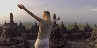 旅游女孩在婆罗浮屠寺拥抱日出的慢动作视频，印度尼西亚。People discovery Asia概念