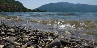 景观拍摄卵石，迎面而来的海浪和山脉。