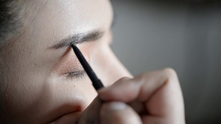 特写的专业化妆师在眼睑上应用眼线视频素材模板下载