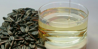 将葵花籽并排放入量杯中，倒入葵花籽油。