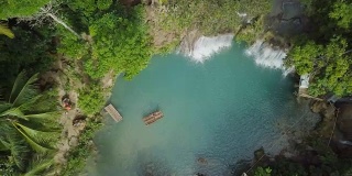 无人机从空中拍摄的年轻女子在热带瀑布竹筏。4K分辨率的视频，在菲律宾拍摄。人们旅行乐趣度假冒险概念