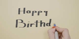 年轻女性用黑色的笔在纸上写下生日快乐